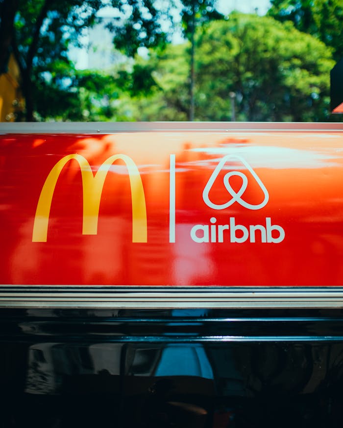 Bright sign showcasing recognizable logos on a vehicle's roof with blurred trees in the background.