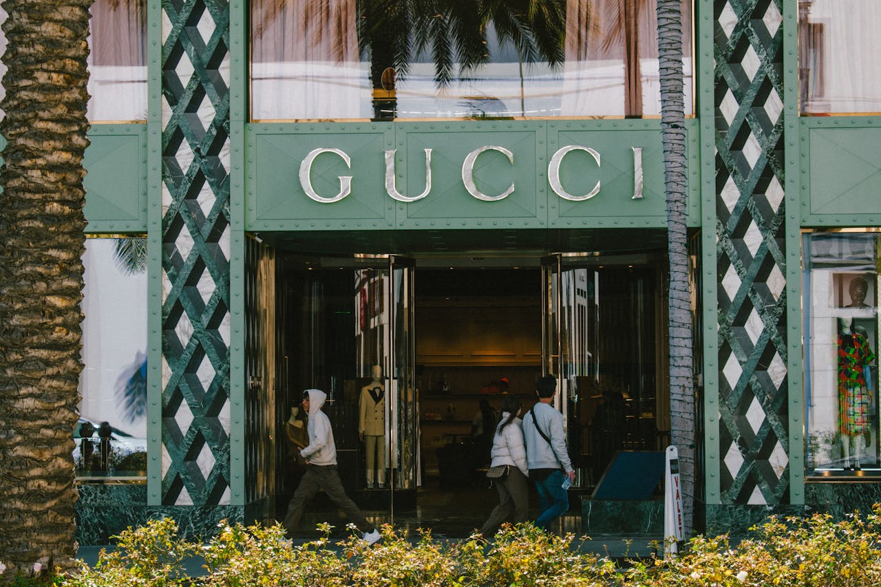 contact-img Gucci store facade with people passing by on a sunny day.