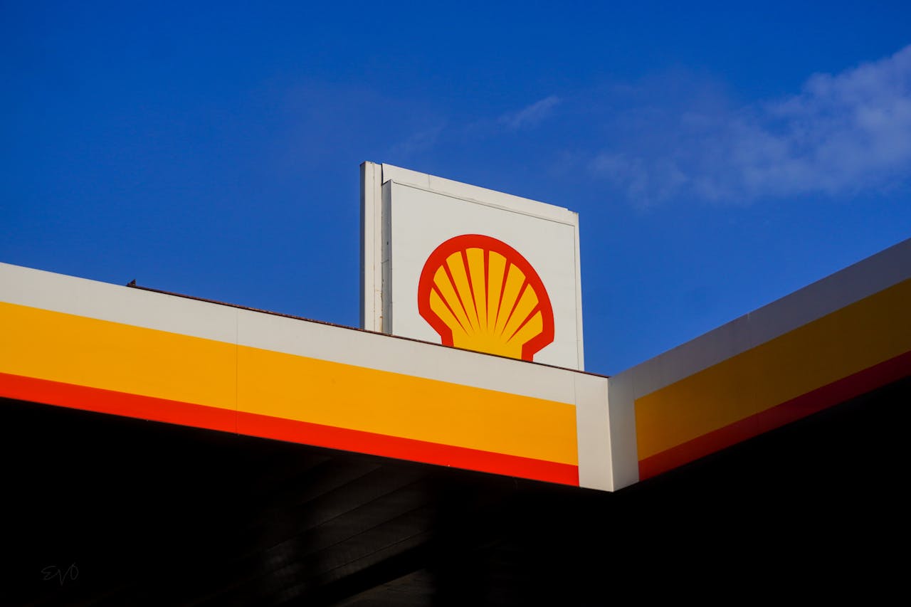 Close-up of a Shell gas station sign in Houston, TX, under a bright blue sky.