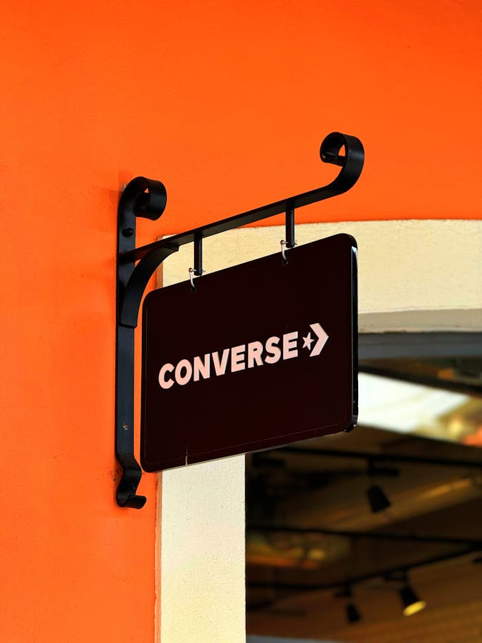 Converse store sign on a vibrant orange wall in Lazio, Italy, daytime view.