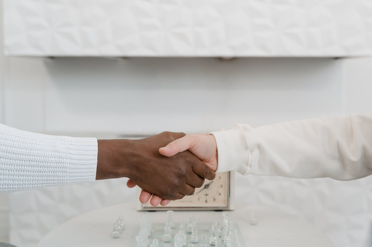 Close-up of an interracial handshake over a chessboard symbolizing unity and strategy.